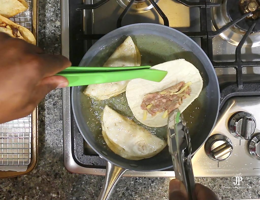 holding tortilla with tongs while beef cooks