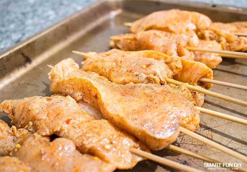 raw chicken skewers on pan