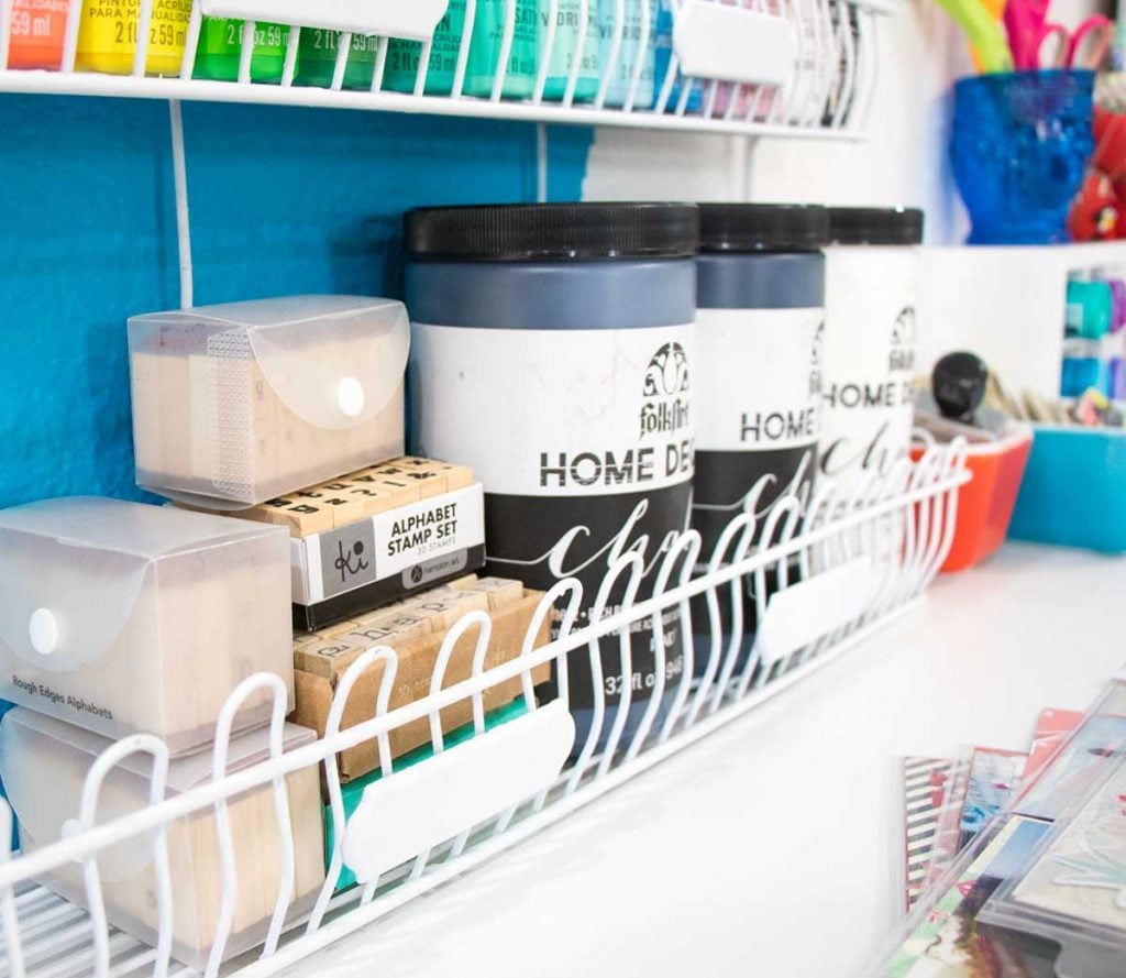 stamps and paint stored in white spray painted wire rack