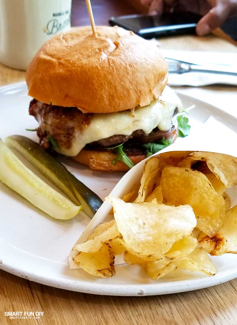 Gaines Brothers Burger with pickle spears and chips at Magnolia Table restaurant