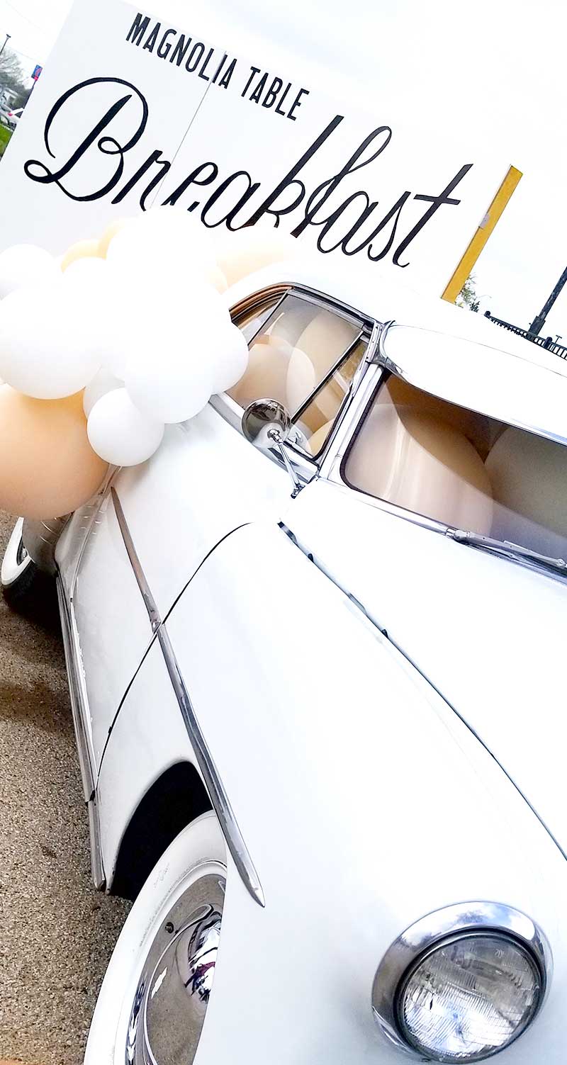 Car and balloons in front of sign that says Magnolia Table Breakfast