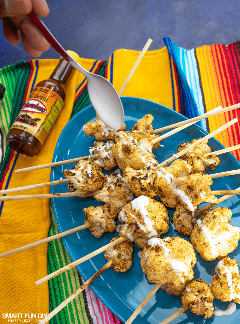 Drizzle crema Mexicanan Drizzling crema Mexican or Mexican sour cream on the cooked cauliflower lollipops with a spoon