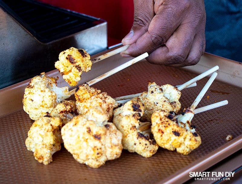 Remove grilled cauliflower lollipops from grill Removing grilled cauliflower lollipops from grill and placing on metal baking sheet