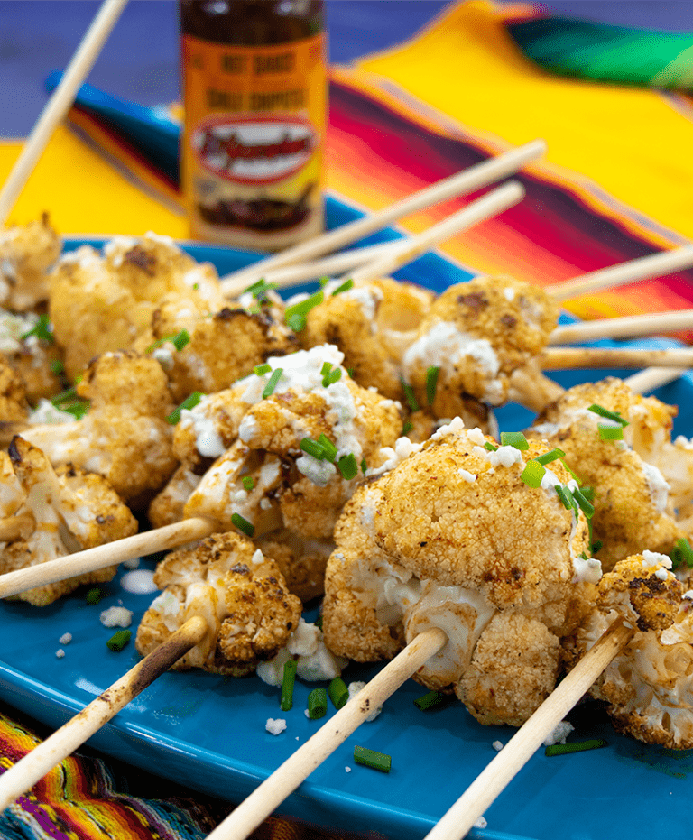 Spicy Cauliflower Lollipops on platter in fron ot El Yucateco hot sauce chile chipotle