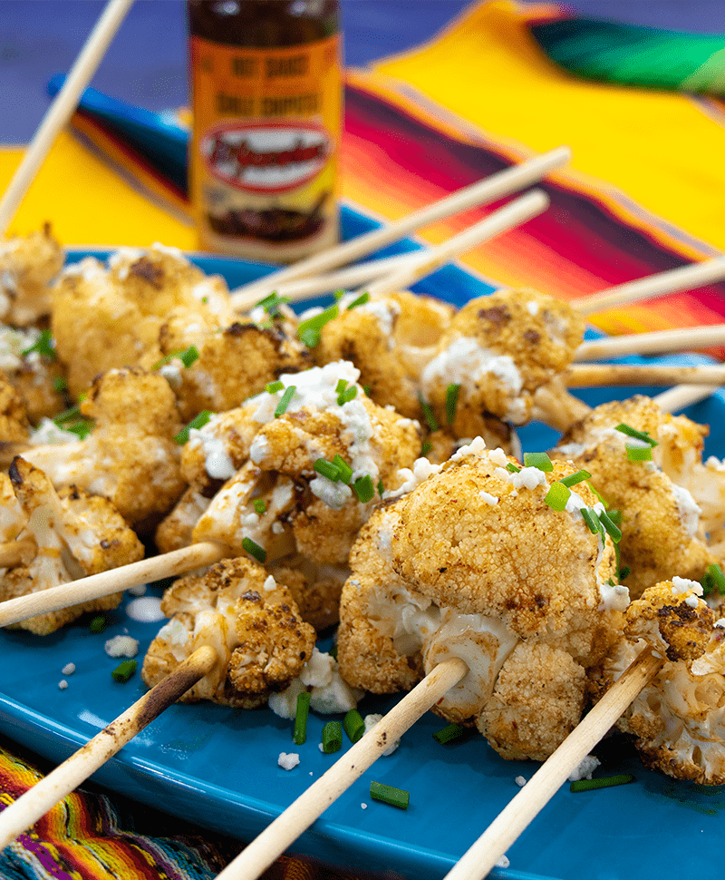 Spicy Cauliflower Lollipops on platter in fron ot El Yucateco hot sauce chile chipotle