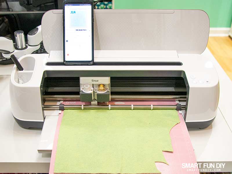 Cricut Maker cutting wool felt with android phone on top of the machine operating Cricut Design Space app