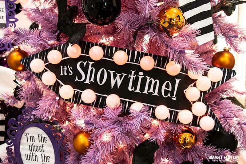 Black wood aroow with sign with words "It's Showtime" and ping pong ball lights around edge