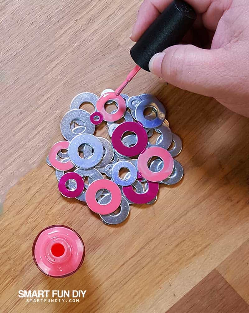 DIY metal washer coaster being painted with pink nail polish