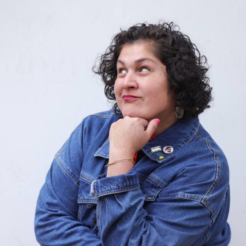 Jennifer Priest in denim jacket with fist under chin